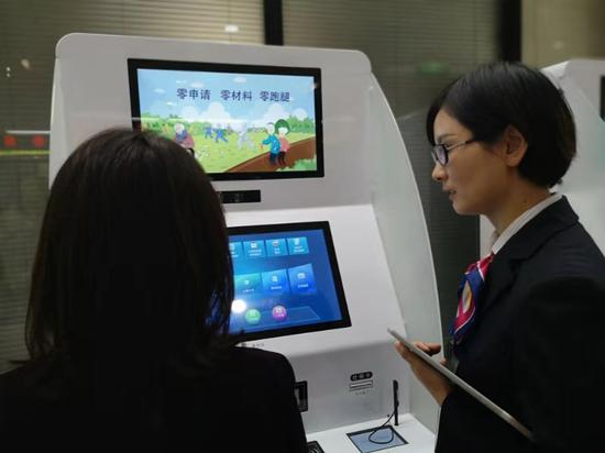 工作人员指导市民使用自助服务机。浙江省人社厅供图